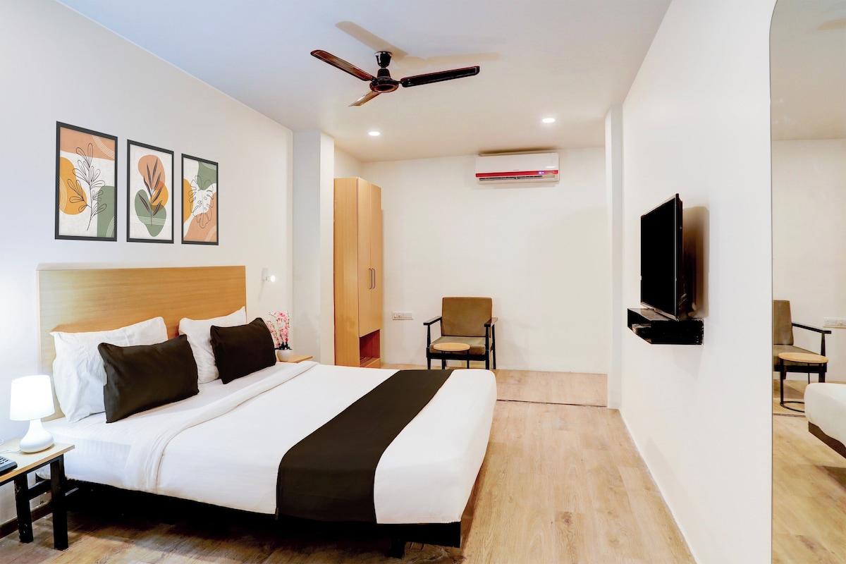 A hotel room with a bed, a desk, a chair, a television, and a ceiling fan.
