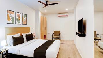 A hotel room with a bed, a desk, a chair, a television, and a ceiling fan.