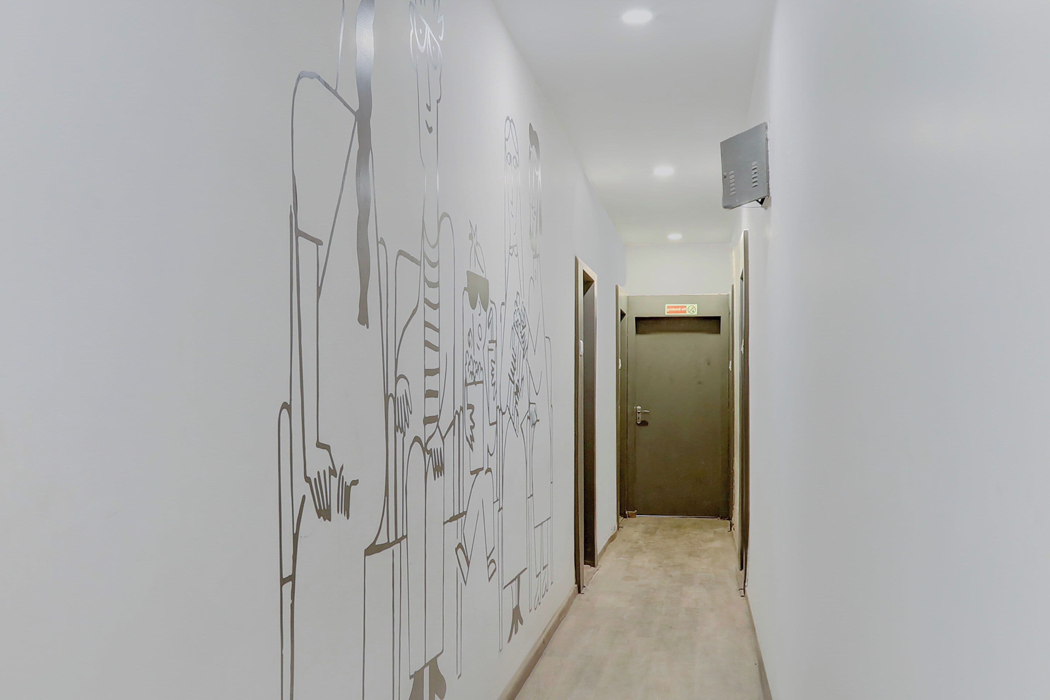 A hallway with a white wall featuring abstract line drawings and a carpeted floor.