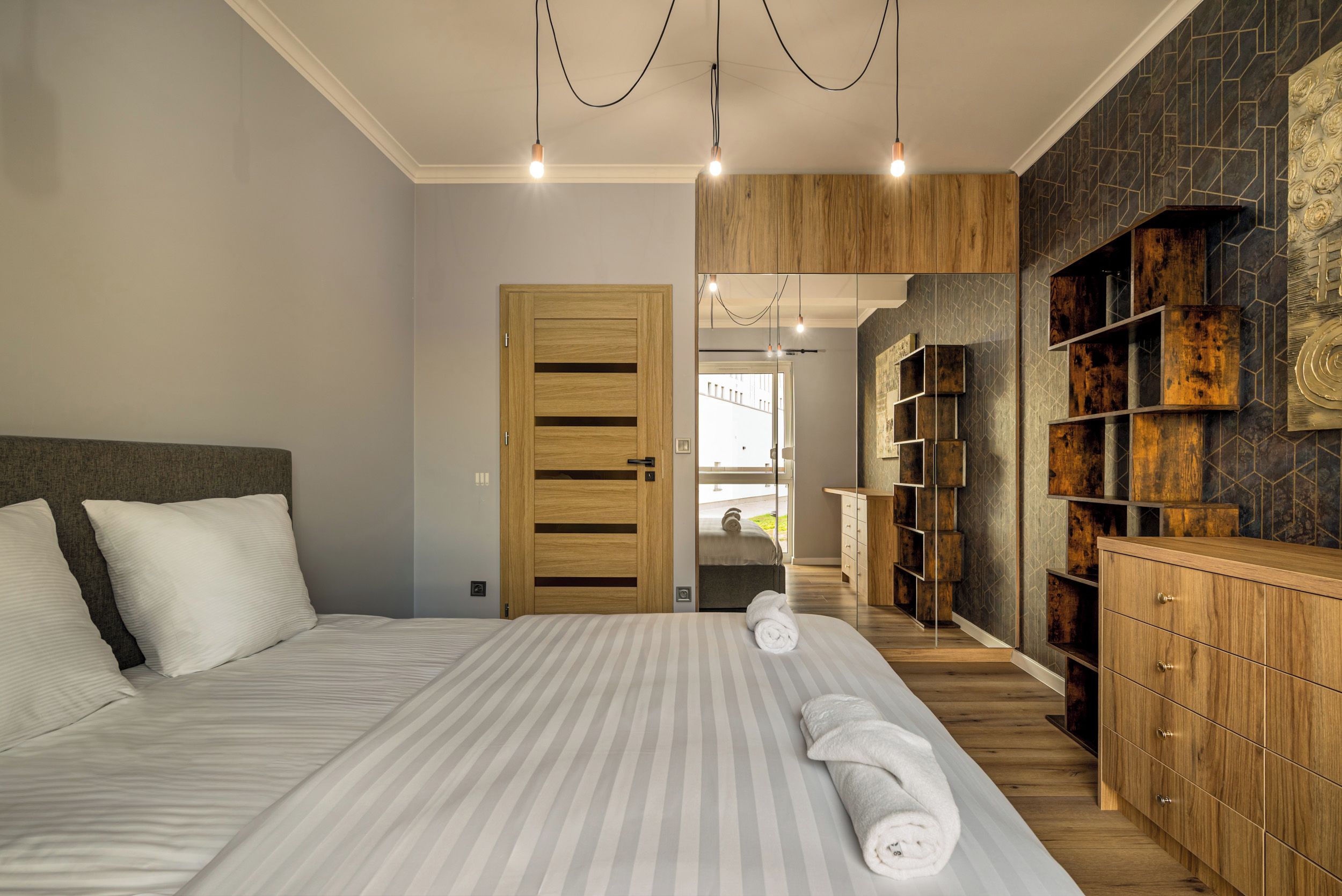 A modern bedroom with a large bed, wooden wardrobe, and a view to the outside.