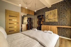 A modern bedroom with a large bed, wooden headboard, built-in shelving, and a geometric-patterned wall. - RentPlanet - Apartamenty Wilkaska (Wrocław)