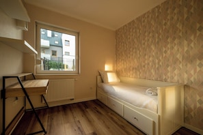 Habitación pequeña con cama, escritorio y radiador.