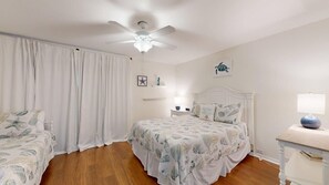 A bedroom with a bed, a ceiling fan, a nightstand, and a window with curtains. - 2-Bedroom 2.5-Bathroom villa located on Hilton Head Island! (Hilton Head)