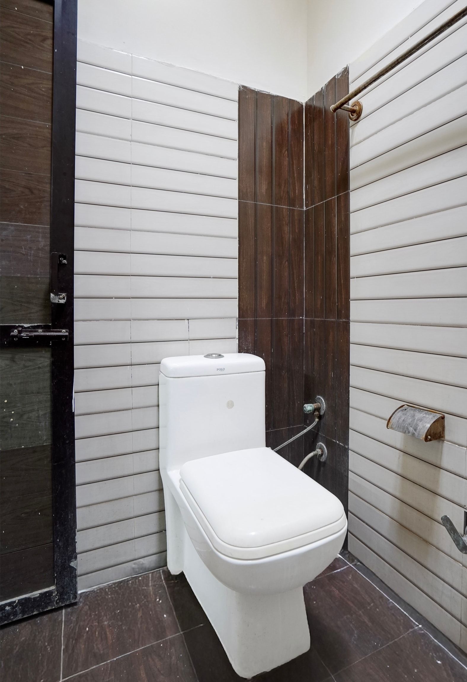 A bathroom with a white toilet, a wooden door, and a tiled wall.