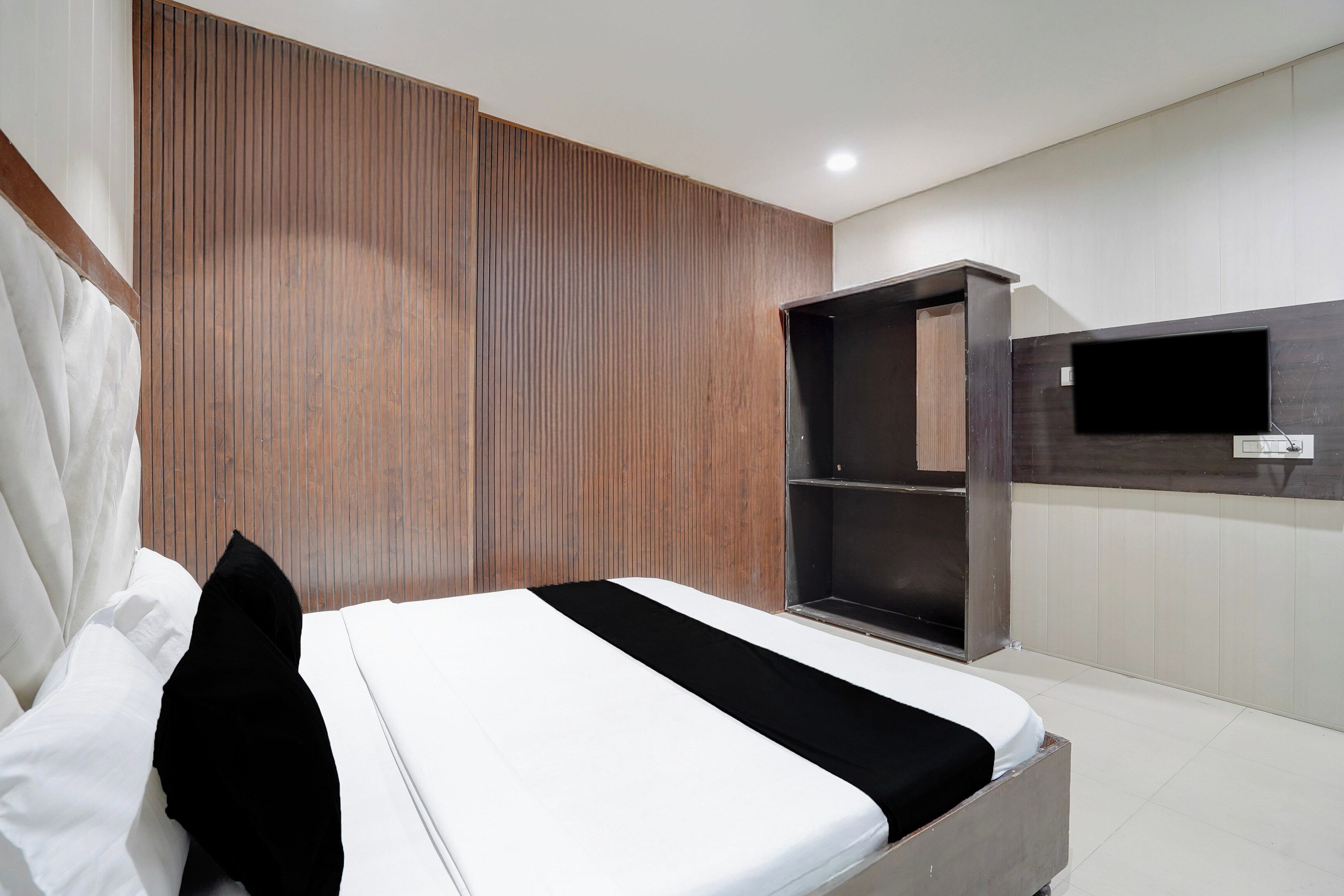 A modern bedroom with a bed, a wardrobe, and a TV mounted on the wall.