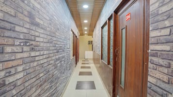 A hallway with brick walls, wooden doors, and a tiled floor.