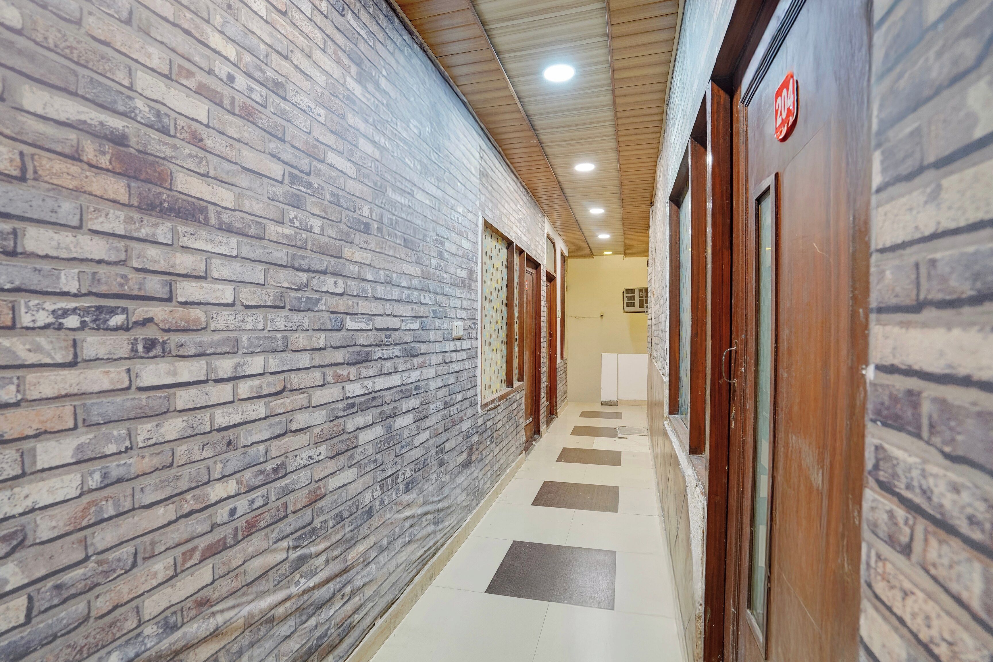 Corredor com paredes de tijolo, portas de madeira e piso ladrilhado.