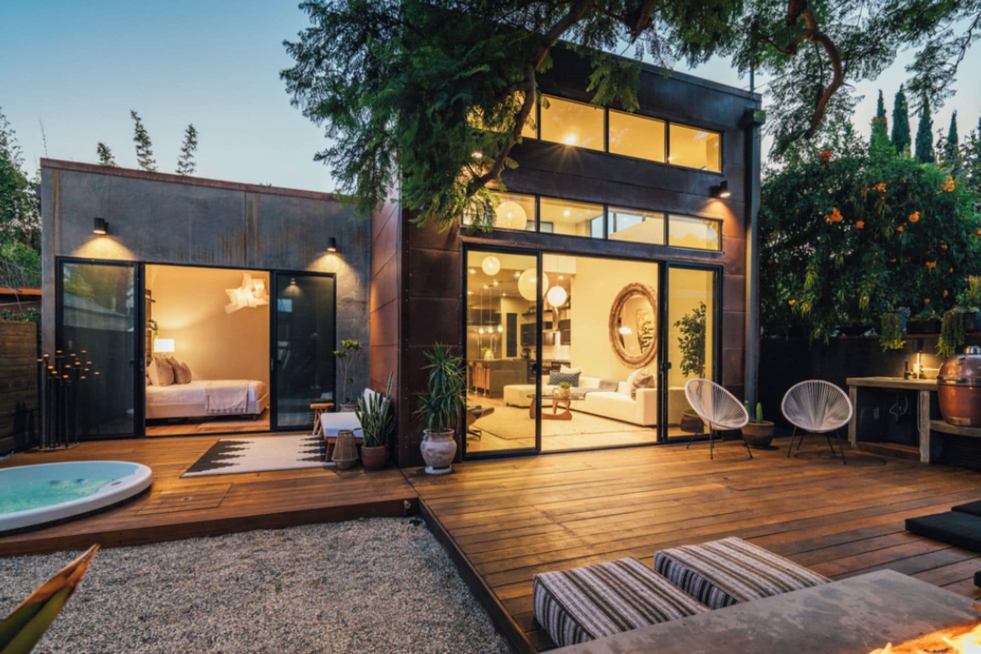 Une maison moderne dotée d’une terrasse en bois, d’une piscine et d’un intérieur bien éclairé.