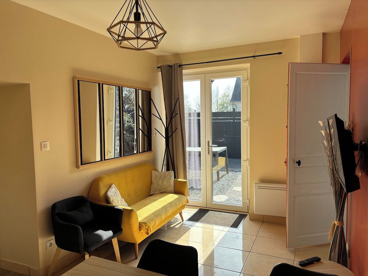 Ein Wohnzimmer mit einer Couch, einem Couchtisch, einem Fernseher und einer Tür, die auf einen Balkon führt.