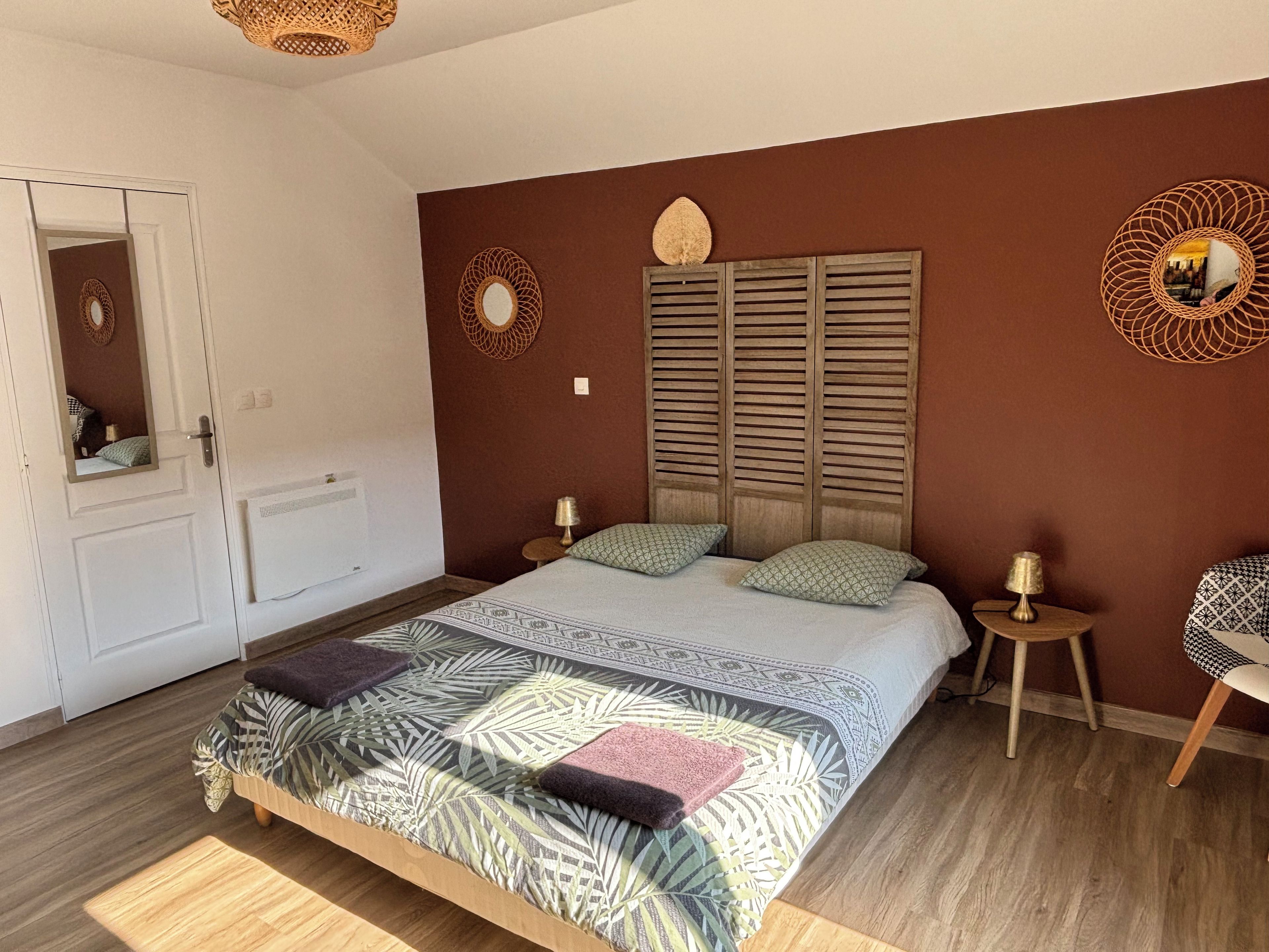 Une chambre à coucher avec un lit, deux tables de chevet, un miroir, un radiateur et une porte.