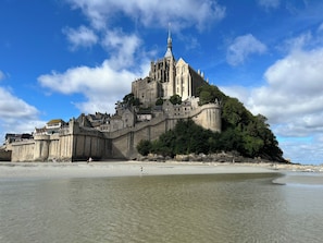 A historic castle on a hill overlooking a beach.