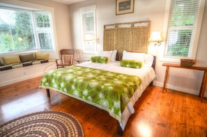 A bedroom with a large bed, a chair, a small table, and a window with blinds. - Kona Mountain Home - Quiet 3 acre property minutes from Beaches and Kailua (Kailua-Kona)