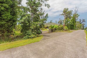 A paved driveway leading to a building with a sloped roof, surrounded by dense greenery and trees. - Kona Mountain Home - Quiet 3 acre property minutes from Beaches and Kailua (Kailua-Kona)