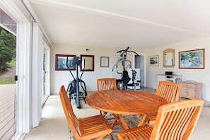 A room with a round wooden table surrounded by chairs, a ceiling fan, exercise equipment, and framed artwork on the walls. - Kona Mountain Home - Quiet 3 acre property minutes from Beaches and Kailua (Kailua-Kona)