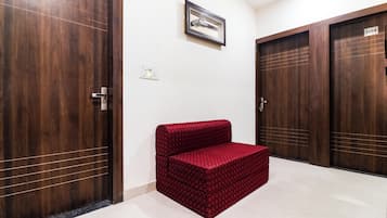A hallway with wooden doors, a red patterned bench, and a framed picture on the wall.
