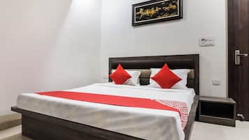 A hotel room with a bed, a nightstand, a door, and a wall-mounted light switch.