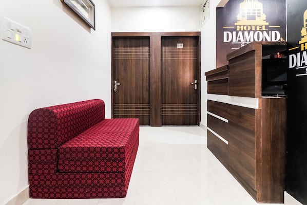 A hotel room with a red patterned sofa, a wooden wardrobe, and a door marked with the number 104.