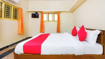 Une chambre d’hôtel avec un lit, une télévision et une fenêtre avec des rideaux.