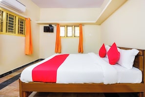 A hotel room with a bed, a television, and a window with curtains. - Hotel O Sai Residency (Hyderabad)