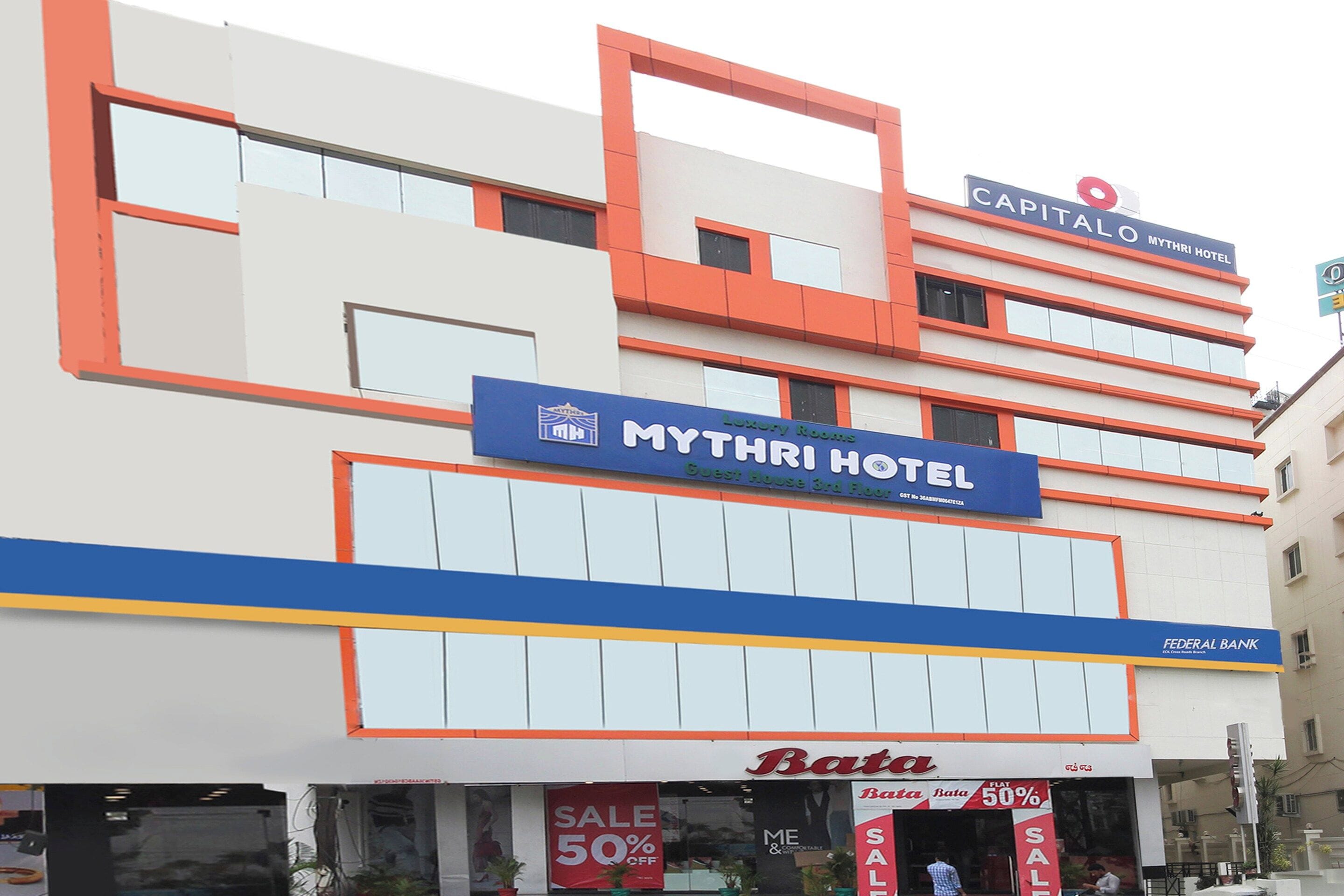 Un hotel amb un rètol que diu 'Mythri Hotel' i una botiga 'Bata' a sota.
