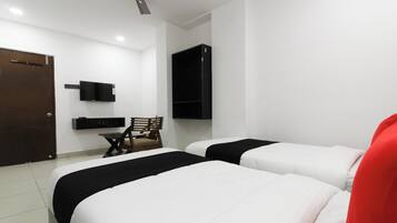 Habitación de hotel con dos camas, un escritorio, una silla, televisor montado en la pared y un ventilador de techo.