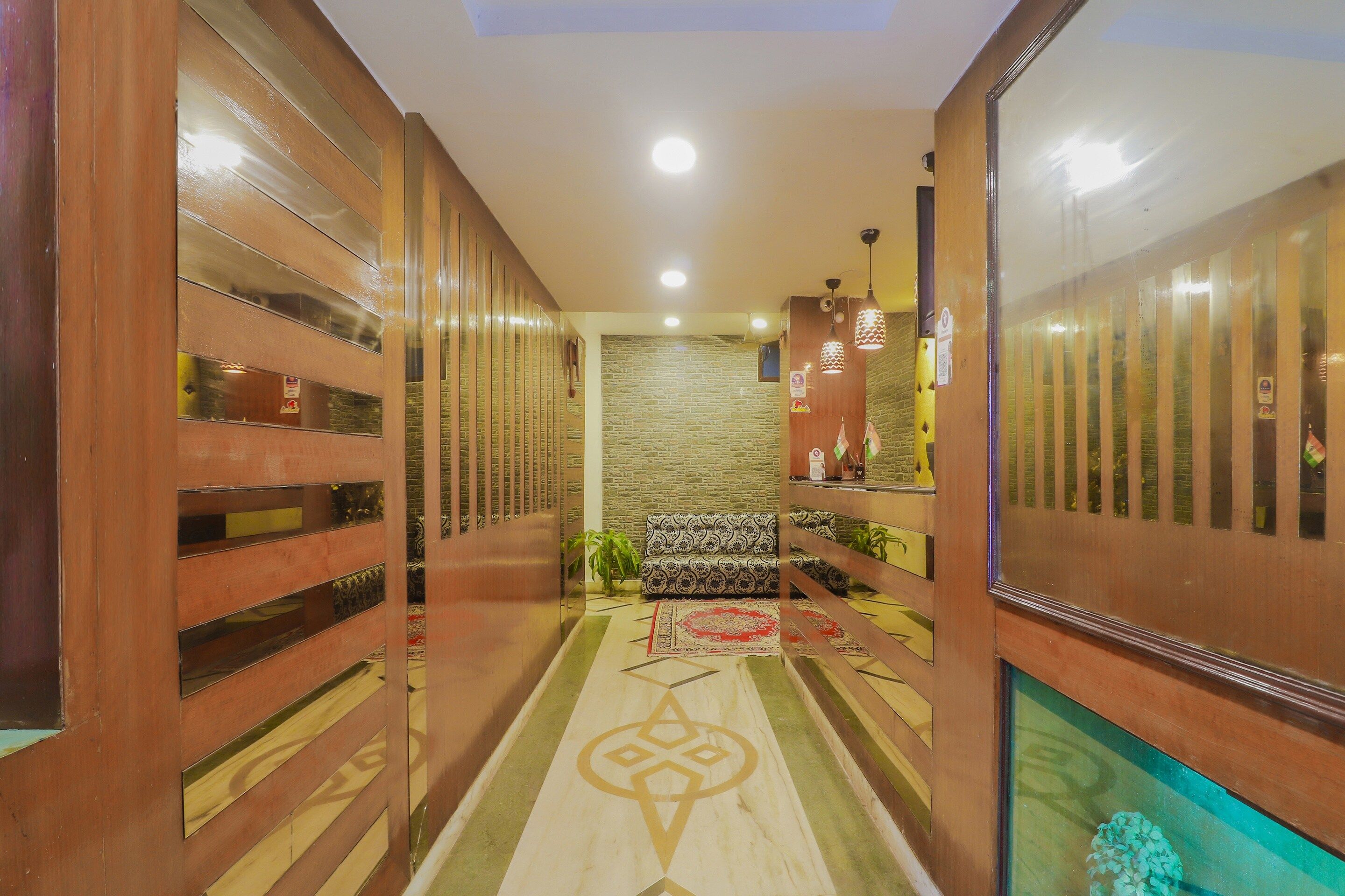 A corridor with wooden paneling, a stone wall, a patterned rug, and a reception desk with a plant.