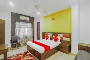A hotel room with a bed, bedside tables, a chair, an air conditioning unit, and a ceiling fan. - Hotel O Meredian comfort inn (Hyderabad)