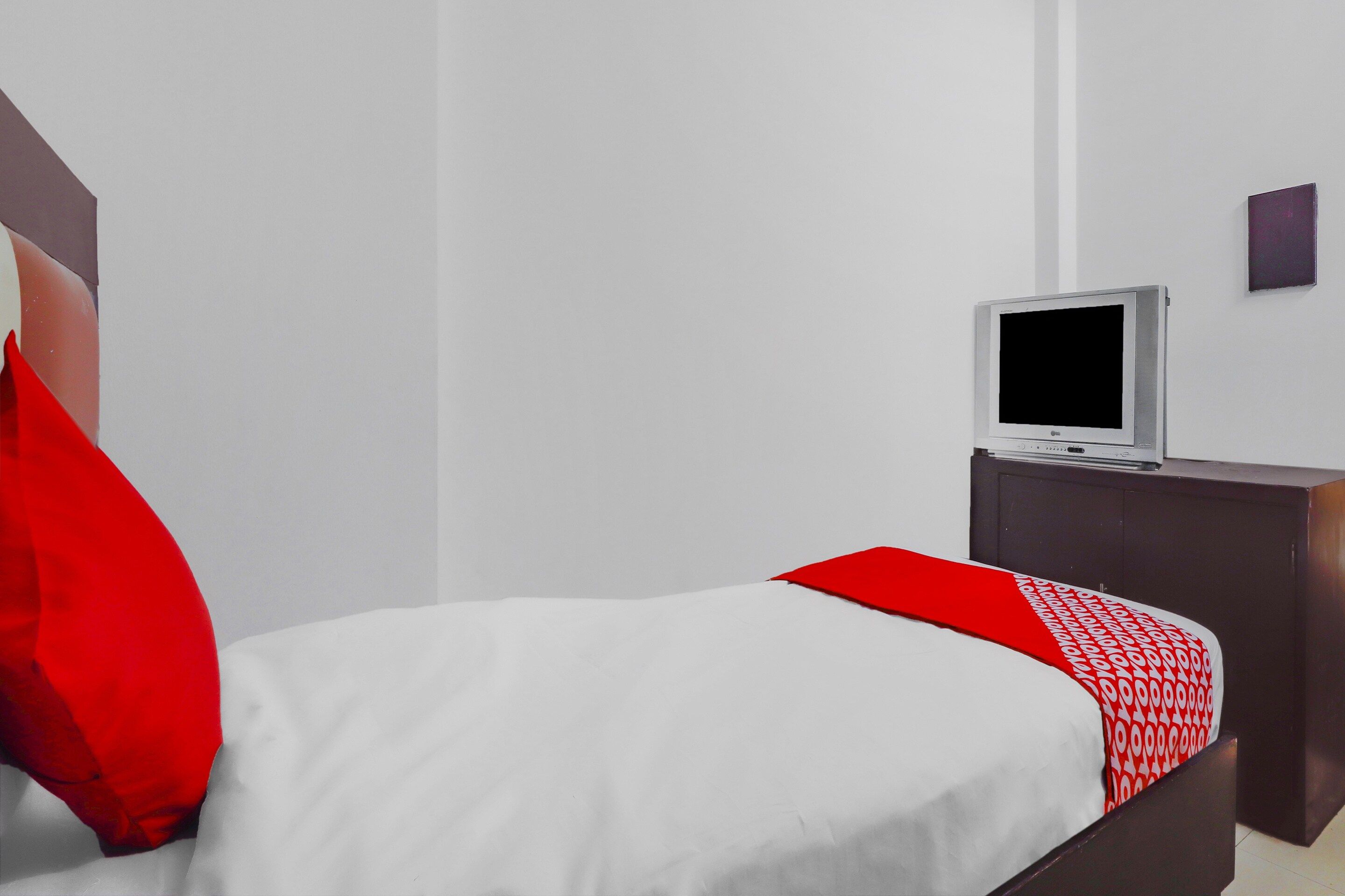 Una habitación de hotel con una cama, un televisor sobre un soporte y una mesita.