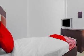 Una habitación de hotel con una cama, un televisor sobre un soporte y una mesita.
