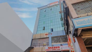 Un edificio de varios pisos con fachada de vidrio moderna, con un letrero visible que dice 'Hotel Meredian' y una tienda para 'Shabbir Gold & Silver Jewellers'.