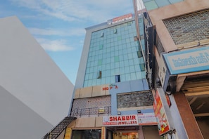 Un edificio de varios pisos con fachada de vidrio moderna, con un letrero visible que dice 'Hotel Meredian' y una tienda para 'Shabbir Gold & Silver Jewellers'.