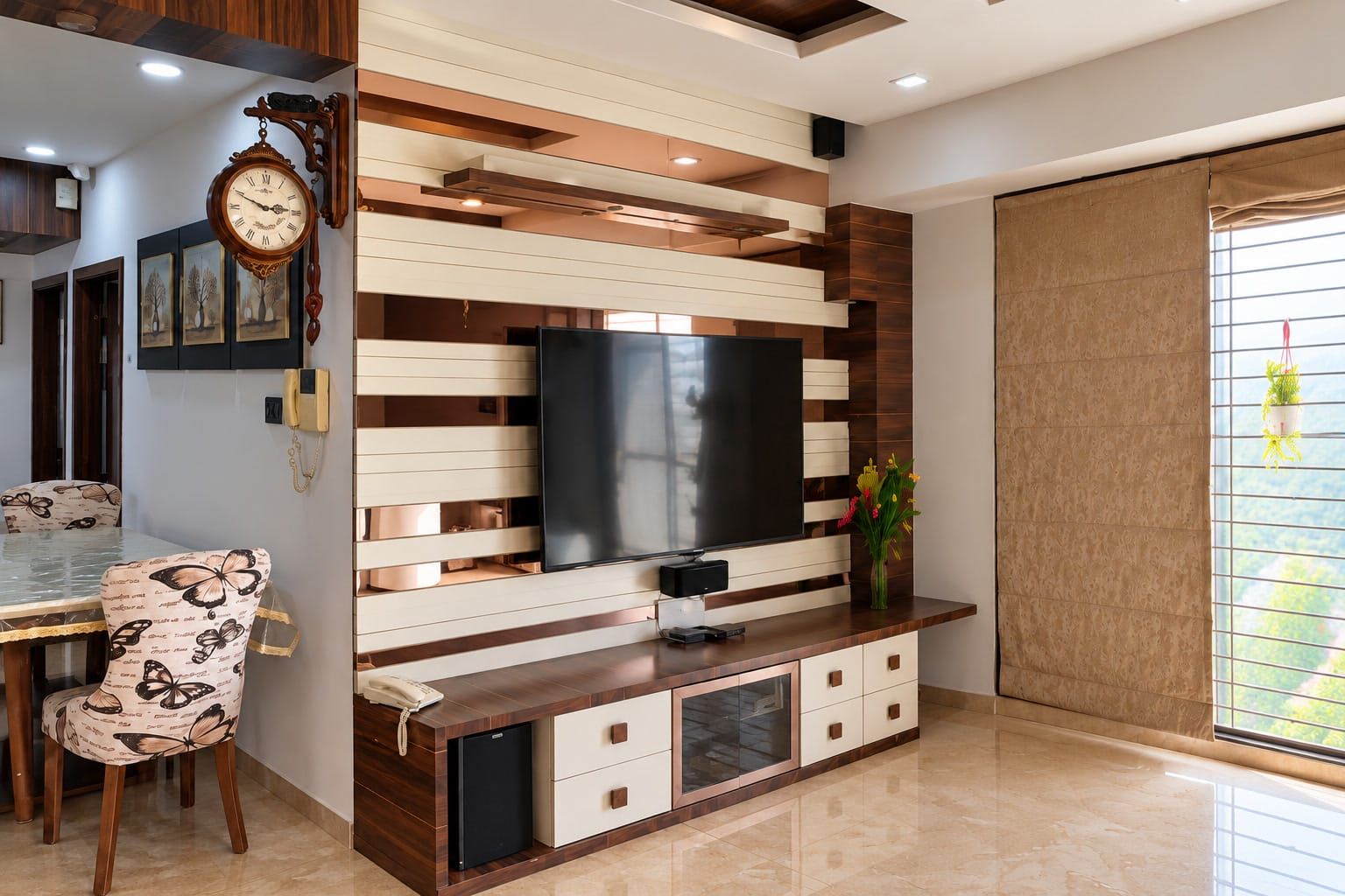 Una sala moderna con televisor de pantalla plana, pared de paneles de madera y blanco, un comedor con una silla estampada de mariposas y un refrigerador pequeño.
