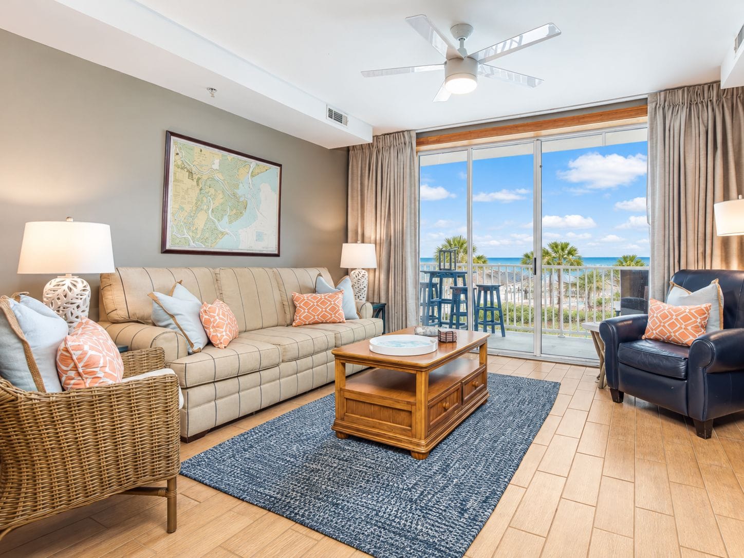 A living room with a sofa, two chairs, a coffee table, and a large window with a view of the ocean.