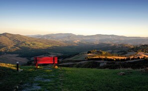A bench overlooking a valley with distant mountains. - New Listing (Volterra)