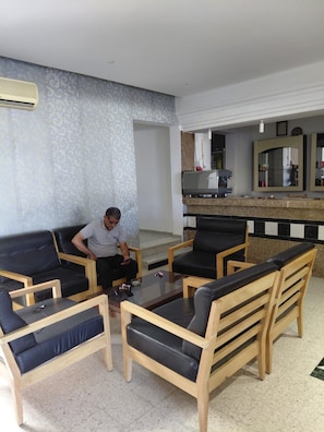 Um saguão de hotel com área de estar, balcão com máquina de café e um espelho grande.