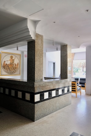 Um hall com coluna de pedra, uma obra de arte emoldurada, uma porta e área de estar.