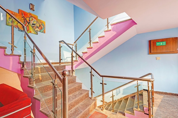 A staircase with glass railings and a fire exit sign. - Hotel O Kanode Gate (Rewari)