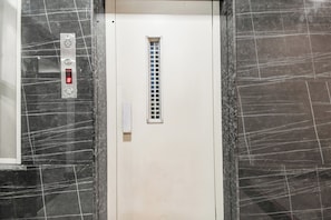 An elevator with a digital display, a control panel, and a vent grille. - Hotel O Raipur City Center (Raipur)
