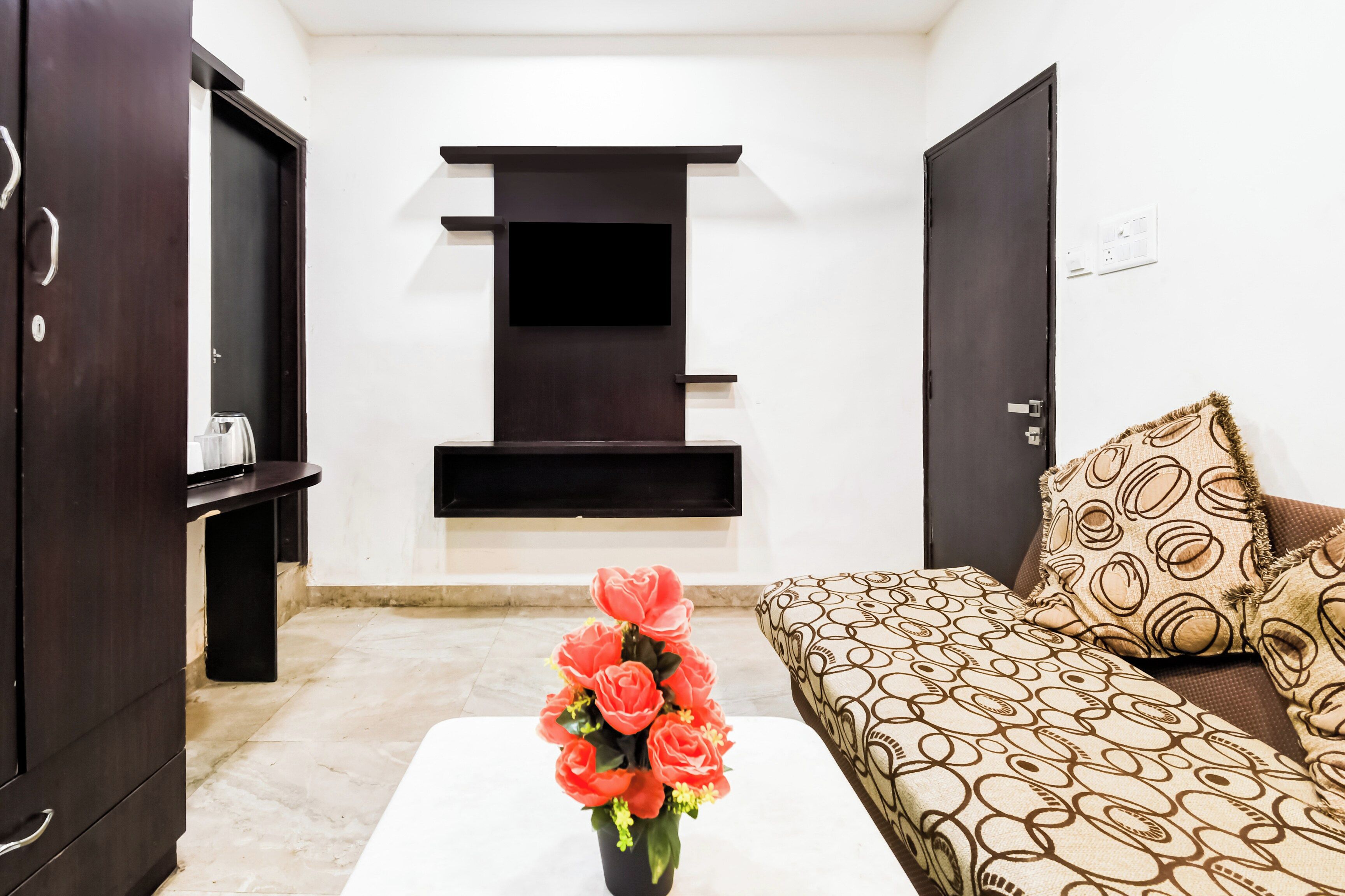Ein Wohnzimmer mit einer Couch, einem Couchtisch mit Blumen und einer dunklen Holzkommode.