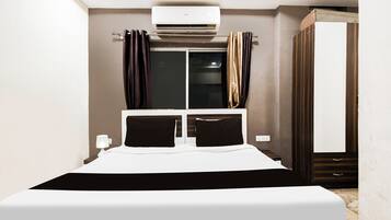 Una habitación de hotel con cama, aire acondicionado, armario y ventana con cortinas.