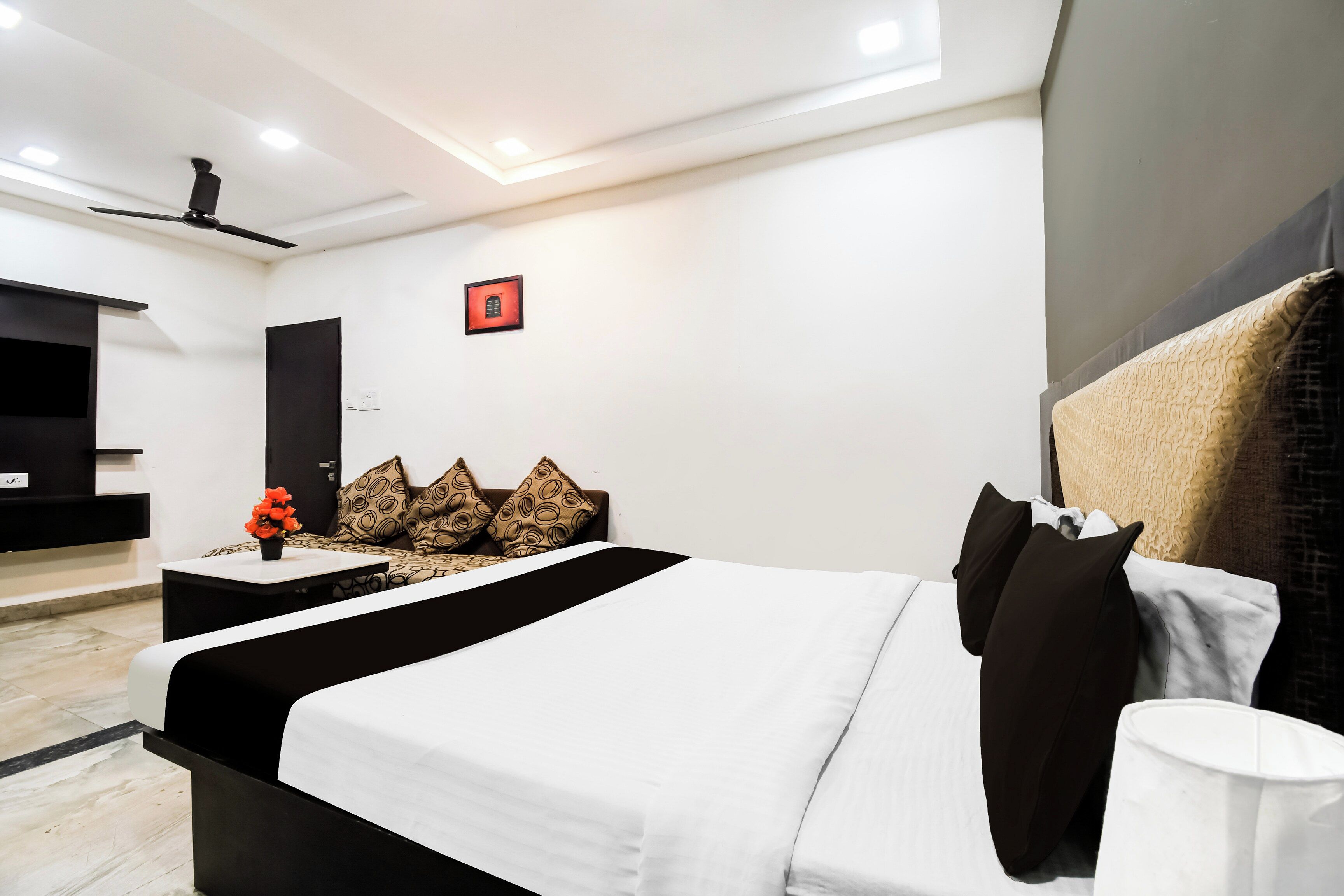 Ein modernes Hotelzimmer mit Bett, Schreibtisch, Stuhl und Deckenventilator.