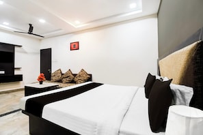 Une chambre d’hôtel moderne équipée d’un lit, d’un bureau, d’une chaise et d’un ventilateur de plafond.