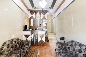 A reception area with a counter, two patterned sofas, a staircase, and a chandelier. - Hotel O by OYO Aadaab (Hyderabad)