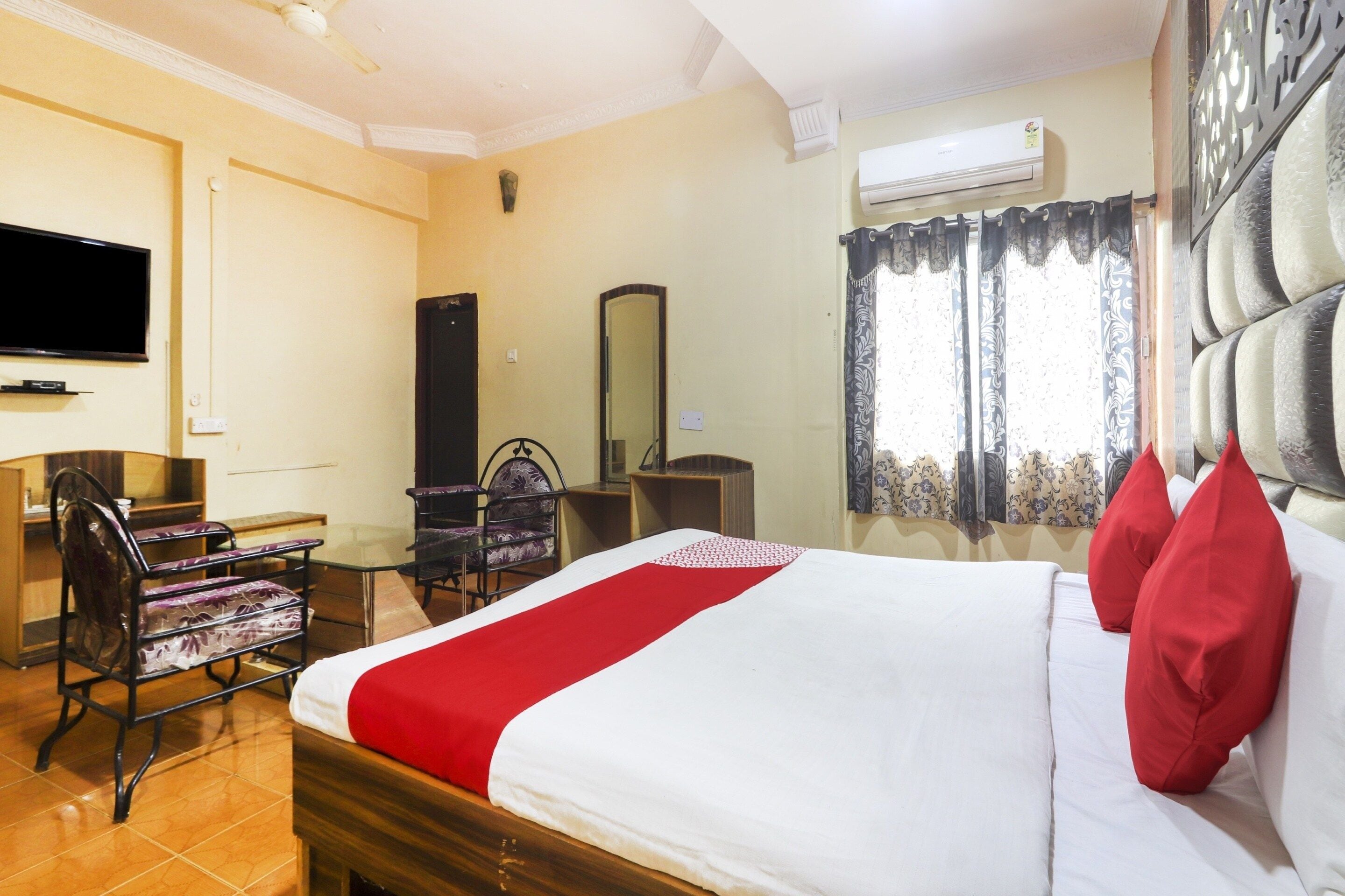 Habitación de hotel con una cama, un escritorio, una silla, un televisor y un equipo de aire acondicionado.