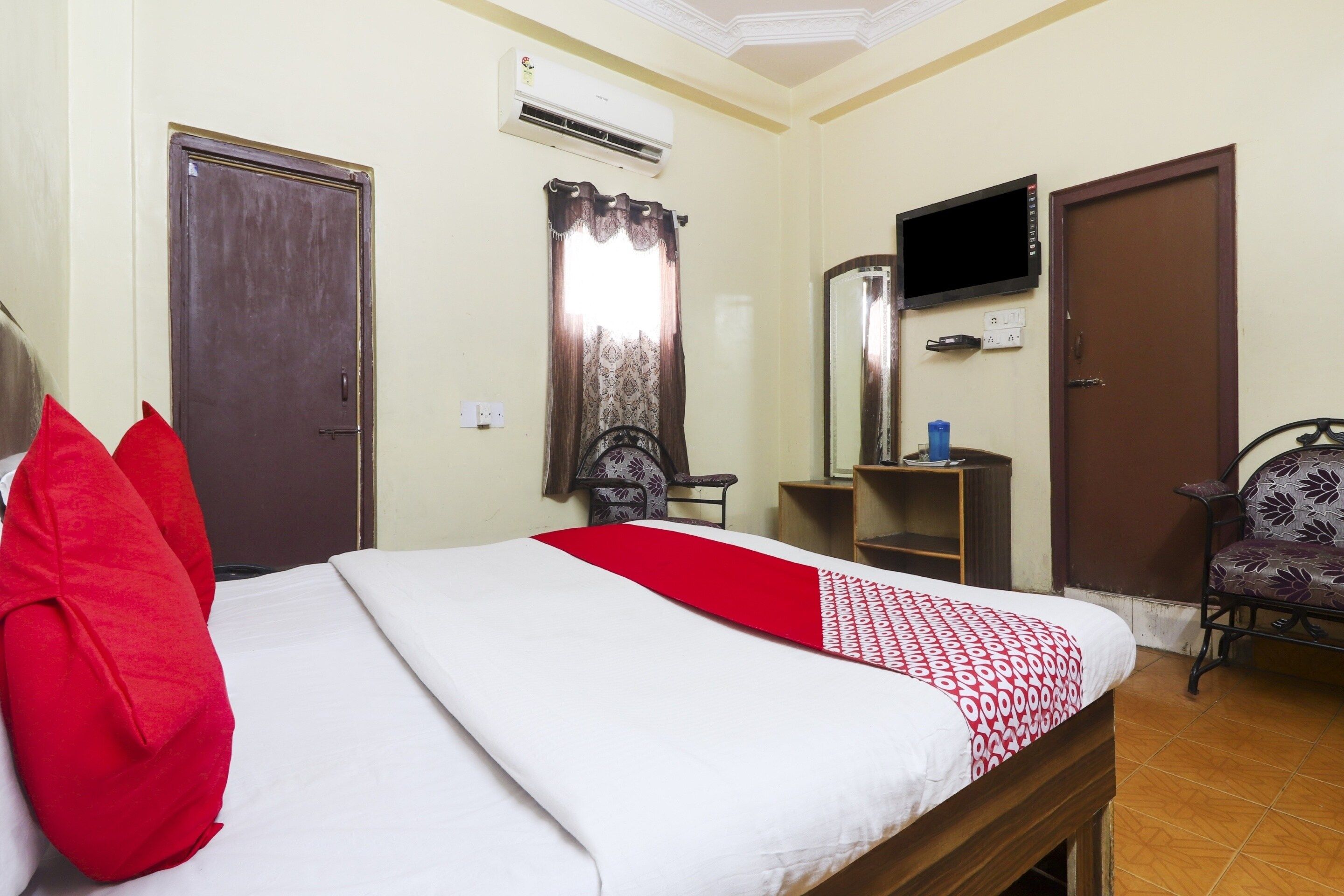 Una habitación de hotel con una cama, televisión, escritorio y una silla.