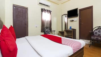 Una habitación de hotel con una cama, televisión, escritorio y una silla.