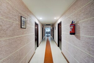 Un pasillo con puertas a ambos lados, un extintor de incendios en la pared y un cuadro en la pared izquierda.