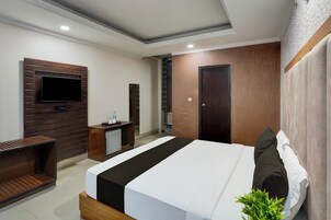 Una habitación de hotel moderna con una cama, televisor, escritorio y armario.