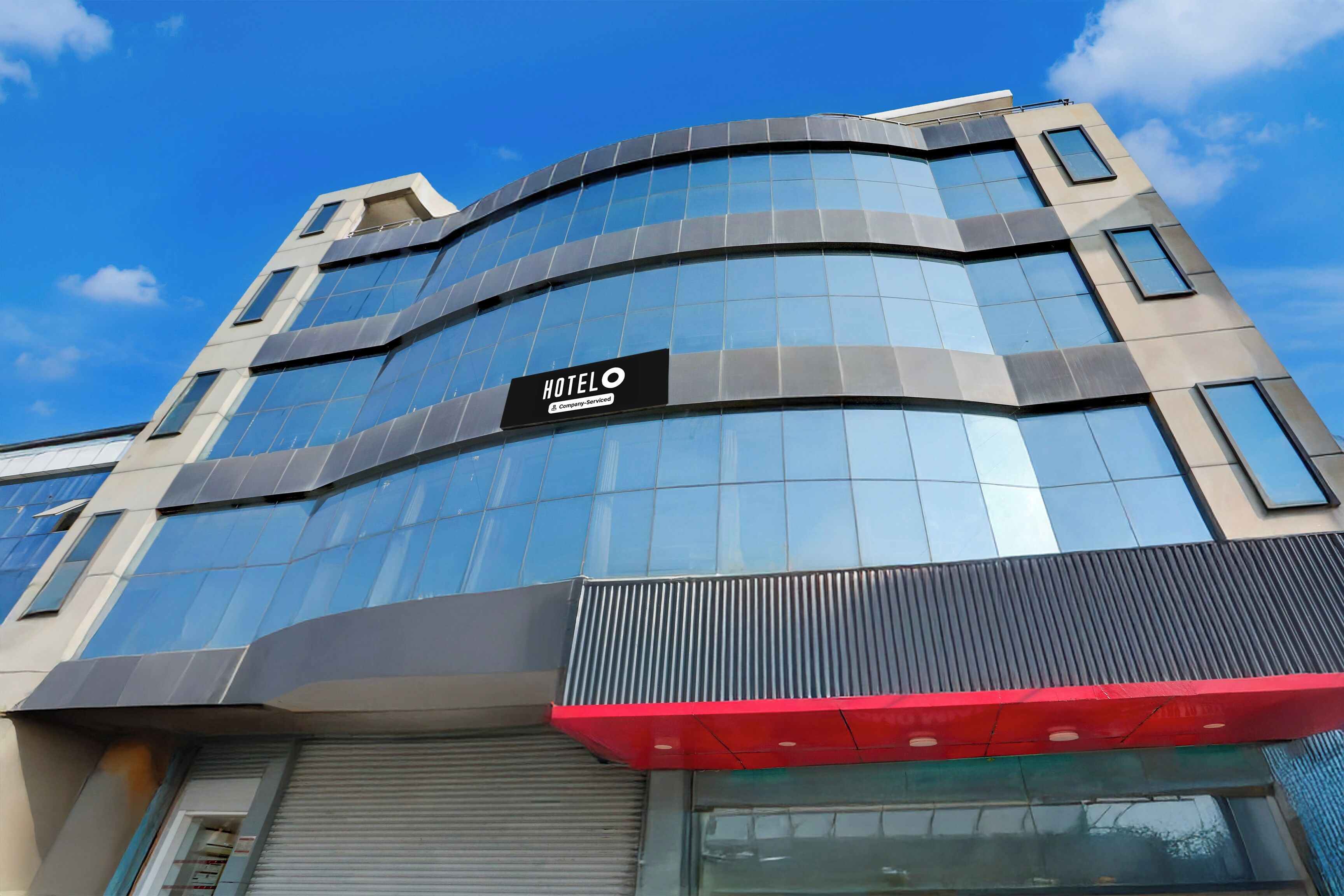 Un moderno edificio de hotel con fachada curva, grandes ventanales y un llamativo letrero que dice 'HOTEL'.