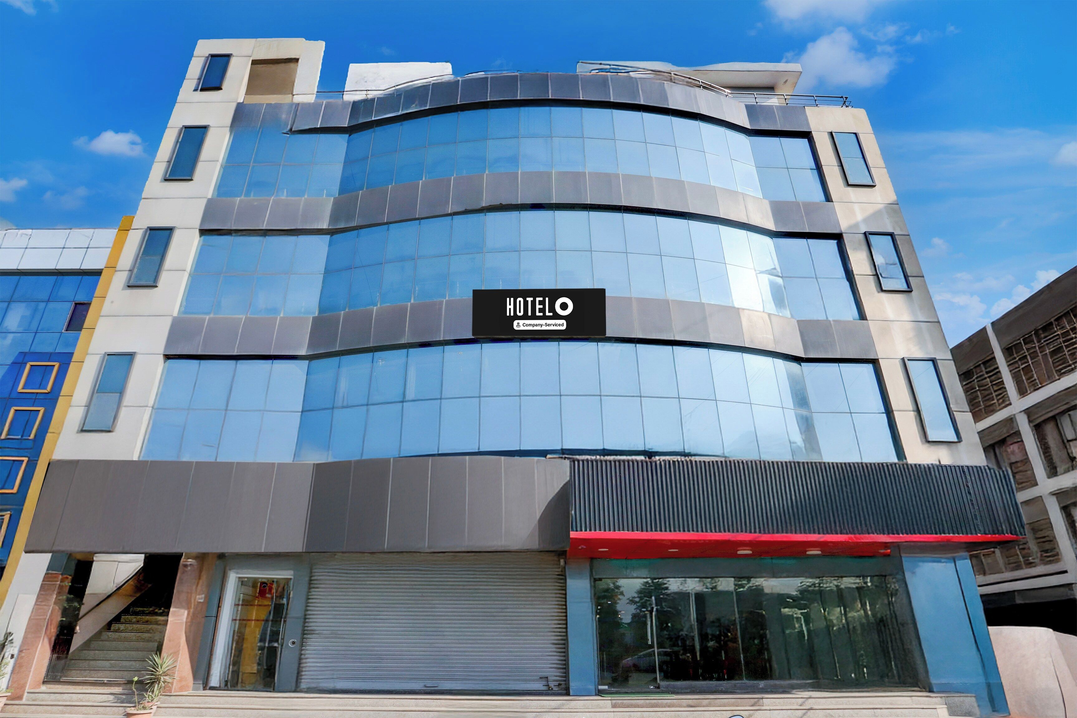A modern hotel with a curved facade, large windows, and a sign indicating it is company serviced.
